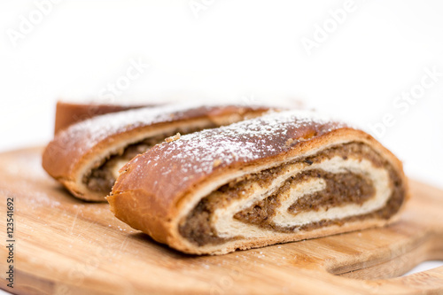 Strudel with walnuts and sugar on the round wooden board