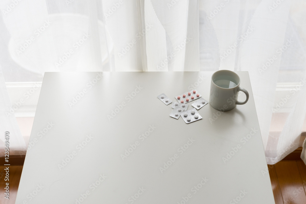 Obraz premium white pills lying next to a glass of water on a wooden table