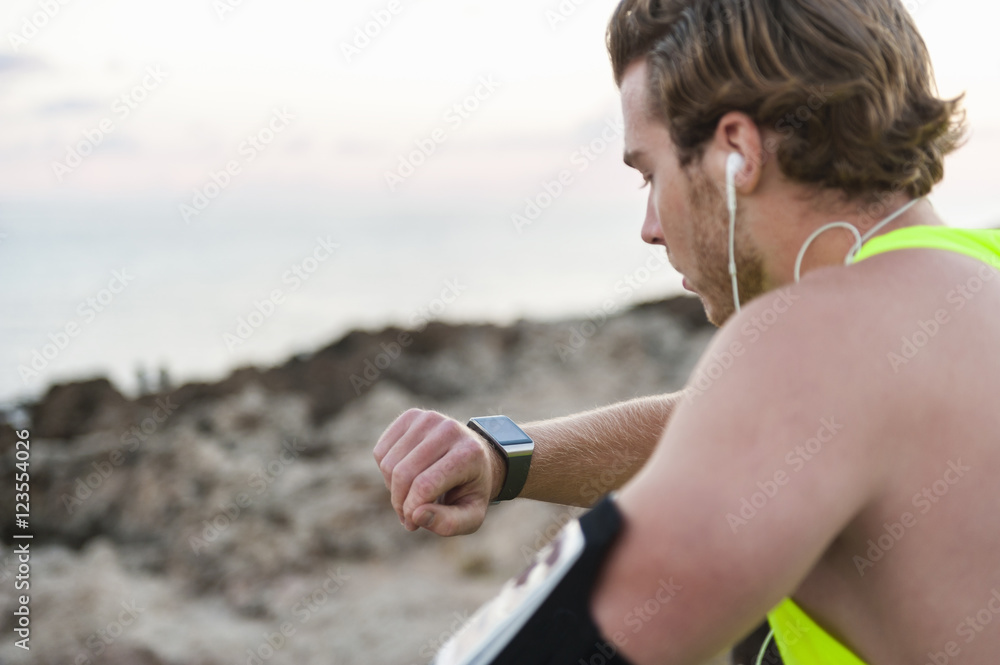 Spain, Mallorca, Jogger at the beach, looking on smartwatch Stock Photo |  Adobe Stock