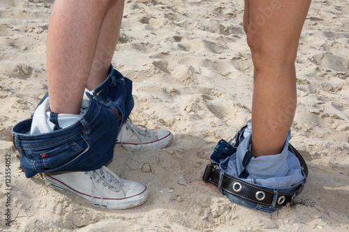 Couple man and woman feet in love romantic outdoor. Legs in jeans and sneakers.