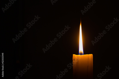 horizontal photo of candle on black background with copyspace on the left