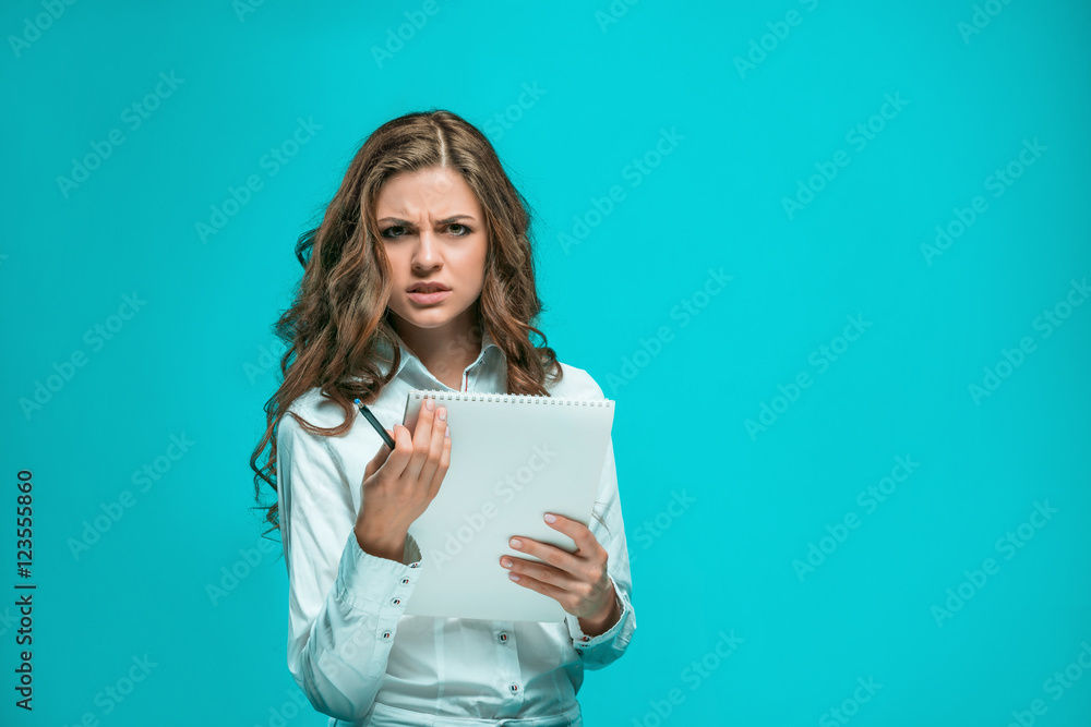 The thoughtful young business woman with pen and tablet for notes on blue background The thoughtful young business woman with pen and tablet for notes on blue background