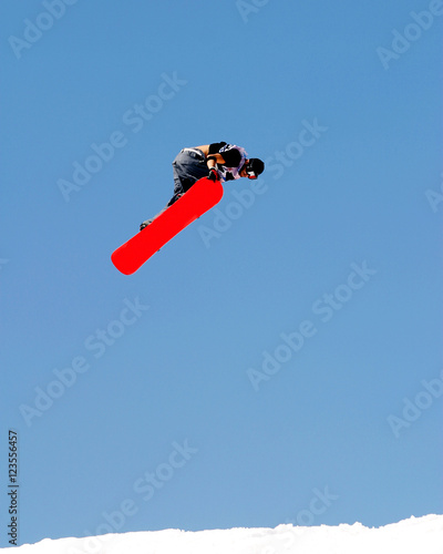 Snowboarder crabbing his Snowboard during a Trick Jump