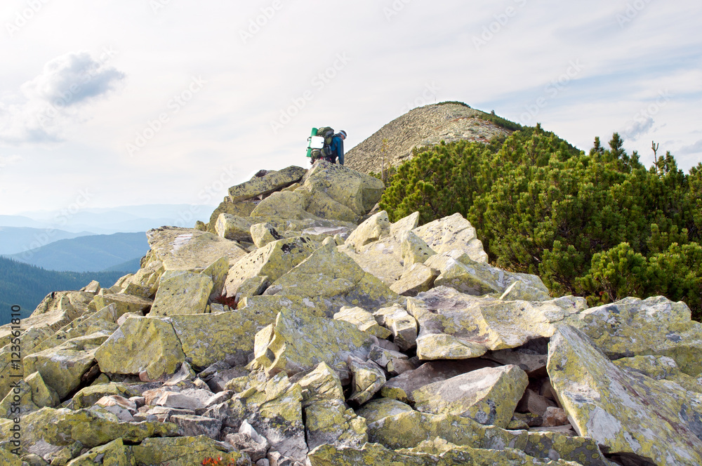 Traveler climbing to the mountain top through boulders Traveler climbing to the mountain top through boulders