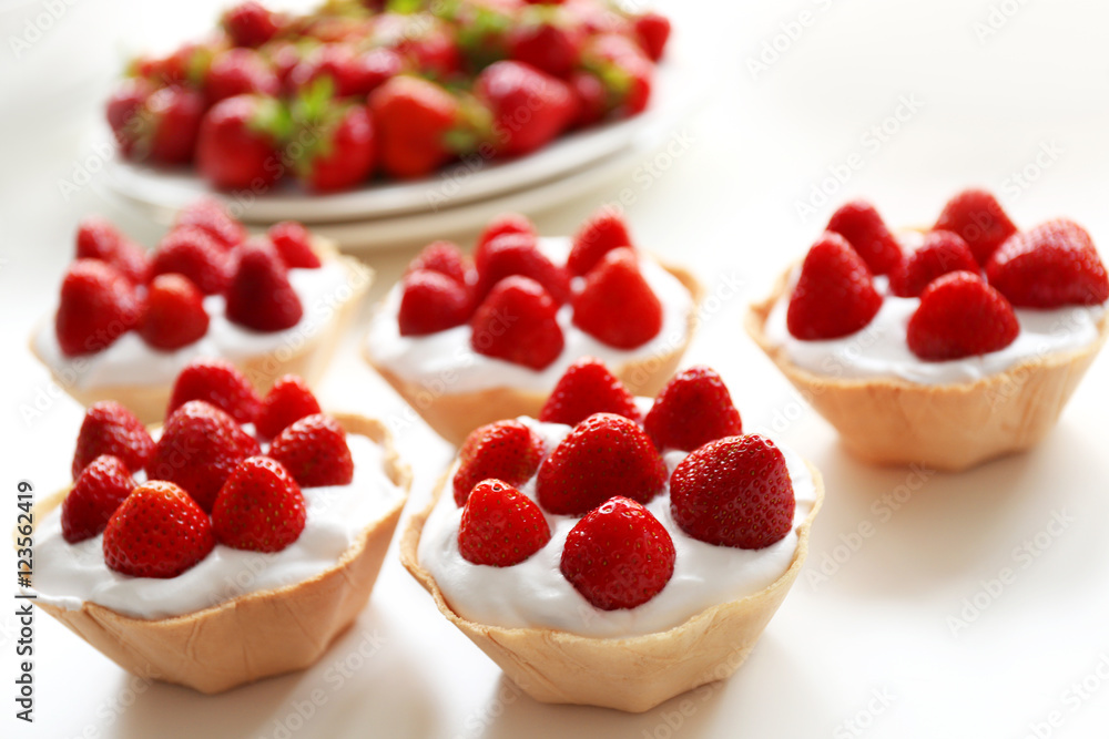 Tasty cakes with strawberries on white table