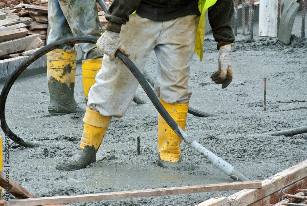 Construction workers using a concrete vibrator at the construction site