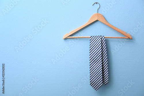 Male tie hanging on the rack, blue background photo