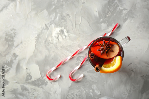 Glass cup of delicious Christmas mulled wine on gray background