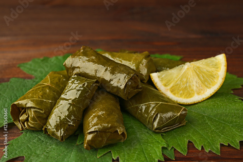 Stuffed delicious Dolma with lemon on vine leaf and wooden background