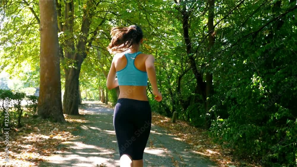Tracking camera of woman girl running jogging in a green park Tracking camera of woman girl running jogging in a green park