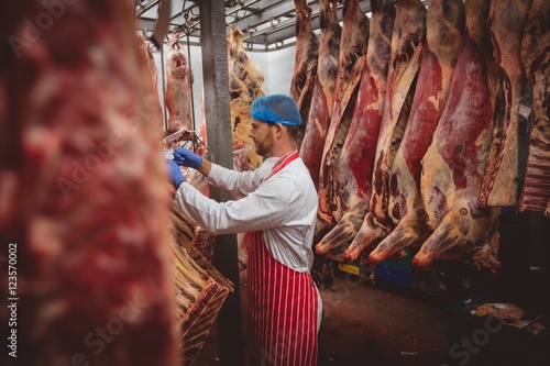 Butcher hanging red meat in storage room