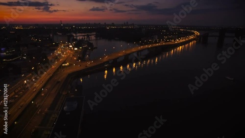 Aerial View of European City at Night with Illuminated Light from Cars, Bridge Over the River. Shot in 4K UHD
