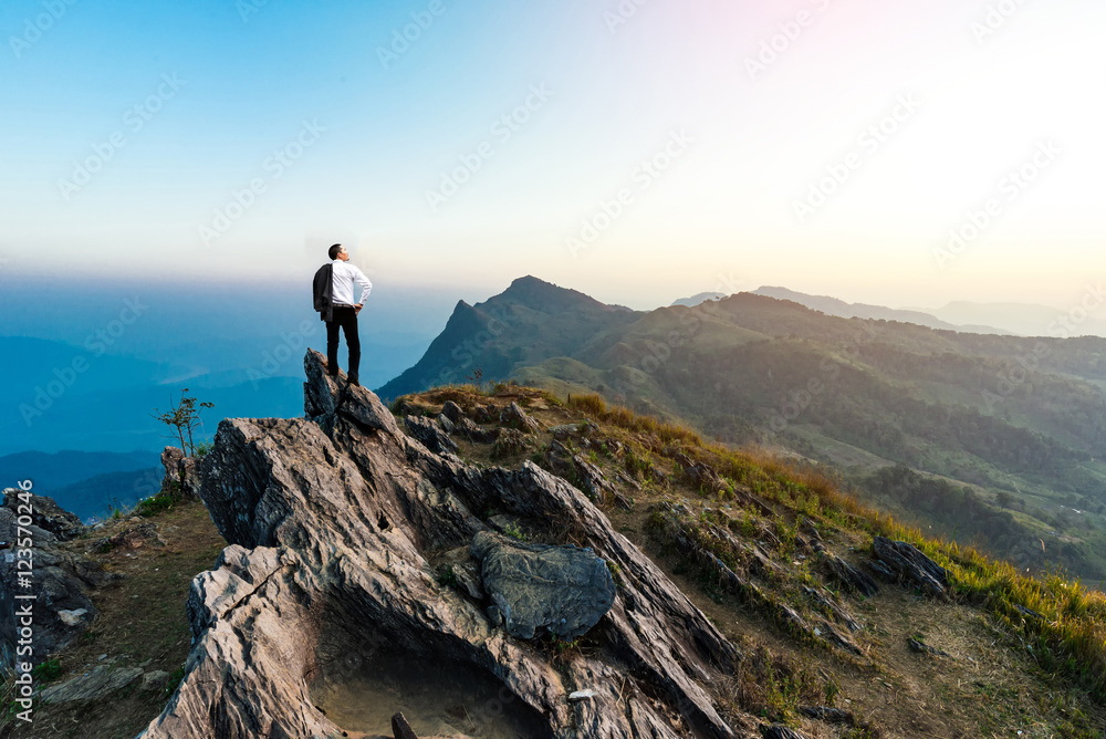 businessman success hiking on the peak of rocks mountain at suns