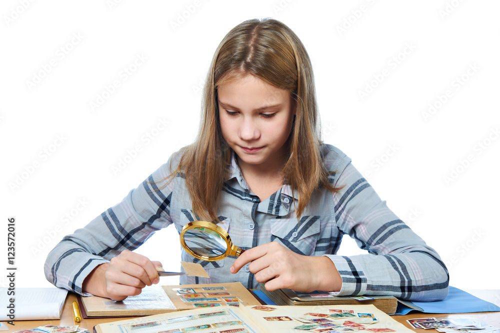 Teen girl with magnifier looks his stamp collection isolated Teen girl with magnifier looks his stamp collection isolated