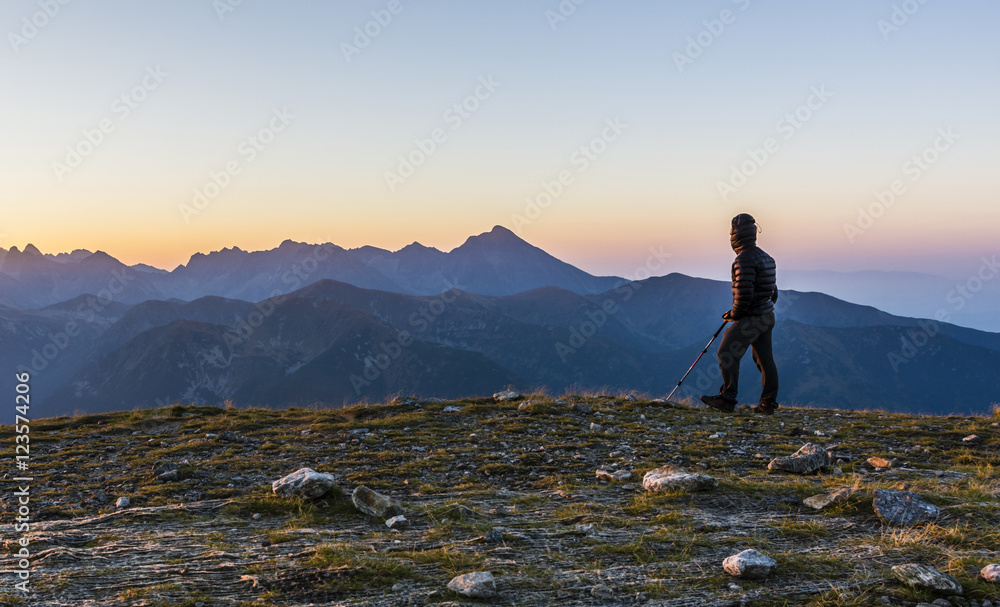 Obraz premium Tourist with trekking poles admire the sunrise.