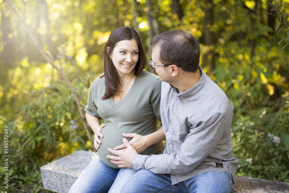 Beautiful pregnant couple relaxing outside in the park. Beautiful pregnant couple relaxing outside in the park.