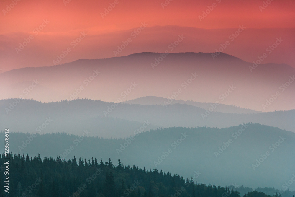 Landscape with colorful layers of mountains and haze  hills covered by forest. The effect of color tinting. Mountains silhouettes.