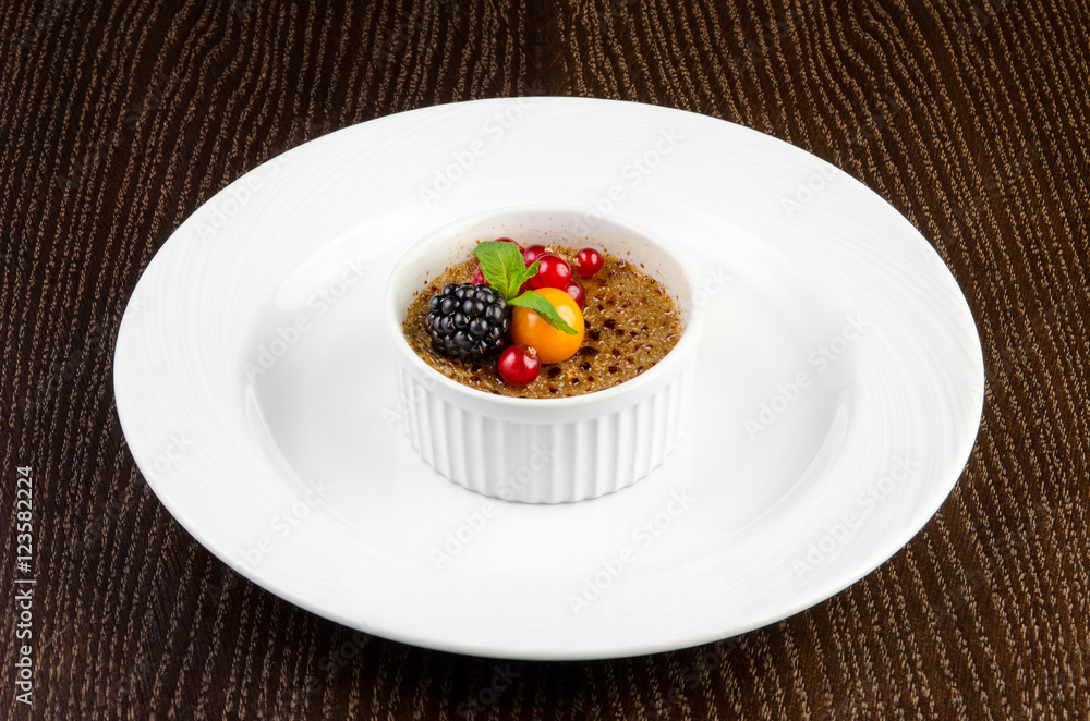 Creme brulee with red currants, blackberries, mint and winter cherry on a dark wooden background Creme brulee with red currants, blackberries, mint and winter cherry on a dark wooden background