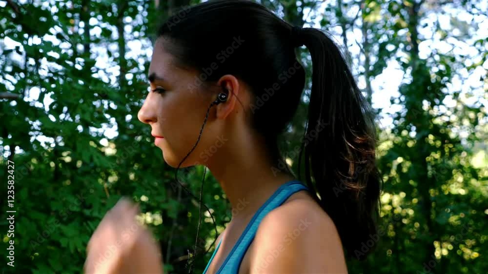Tracking camera of woman girl with headphones running jogging in park, wood, forest Tracking camera of woman girl with headphones running jogging in park, wood, forest