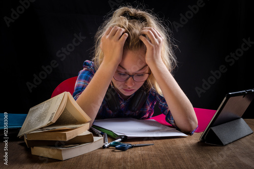 Foto une adolescente , la tête dans les mains, est en difficulté devant ses devoirs s