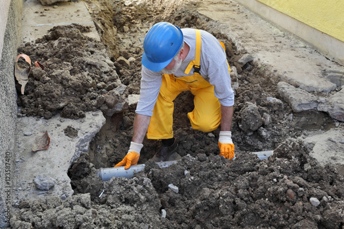 Фотография Plumber fixing sewerage pipe at construction site, home renovation