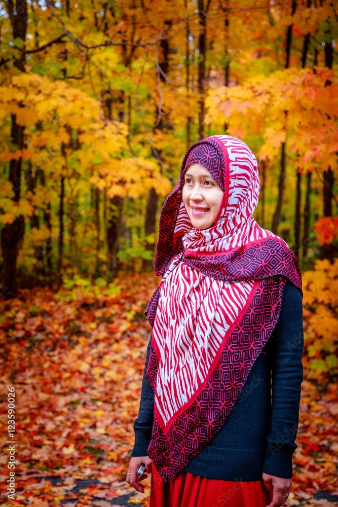 Muslim woman in Canada during autumn with colorful maple leaf as background Muslim woman in Canada during autumn with colorful maple leaf as background