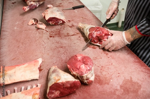 Mid section of butcher cutting pigs head with a knife photo