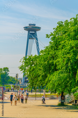 Canvas Print people are walking through an alley towards the SNP bridge in Bratislava, Slovak