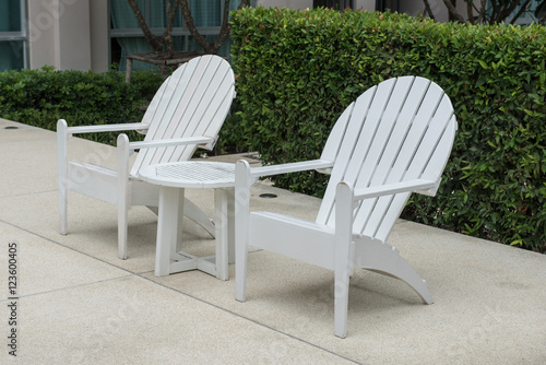 plastic chair on swimming pool side with garden in outdoor design. Image of white plastic chairs by the swimming pool use for background