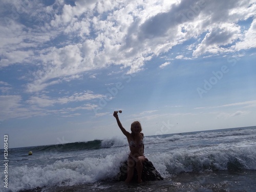 attractive young woman sits on the rock in the sea