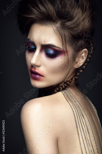 Beautiful woman portrait on black background. Young lady posing from spine with glamour make up and hairstyle.