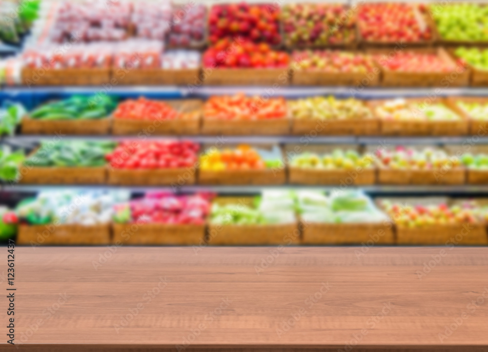 Wooden empty table in front of blurred supermarket fruits shelf