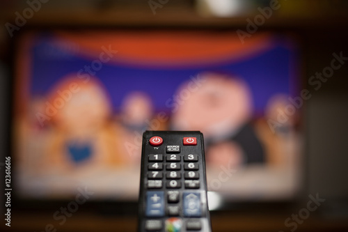 Black TV remote in front of the smart TV (color toned image)