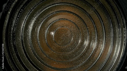 Spotlight with Fresnel lens slowly turn off in front of black background.