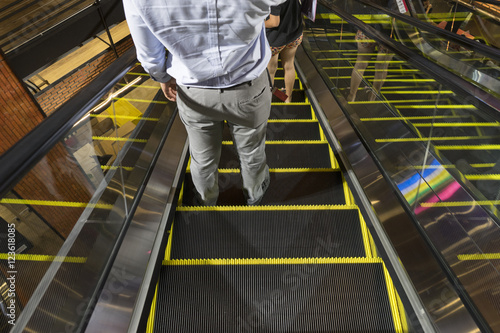 man stand on escalator downstairs in shoping mall