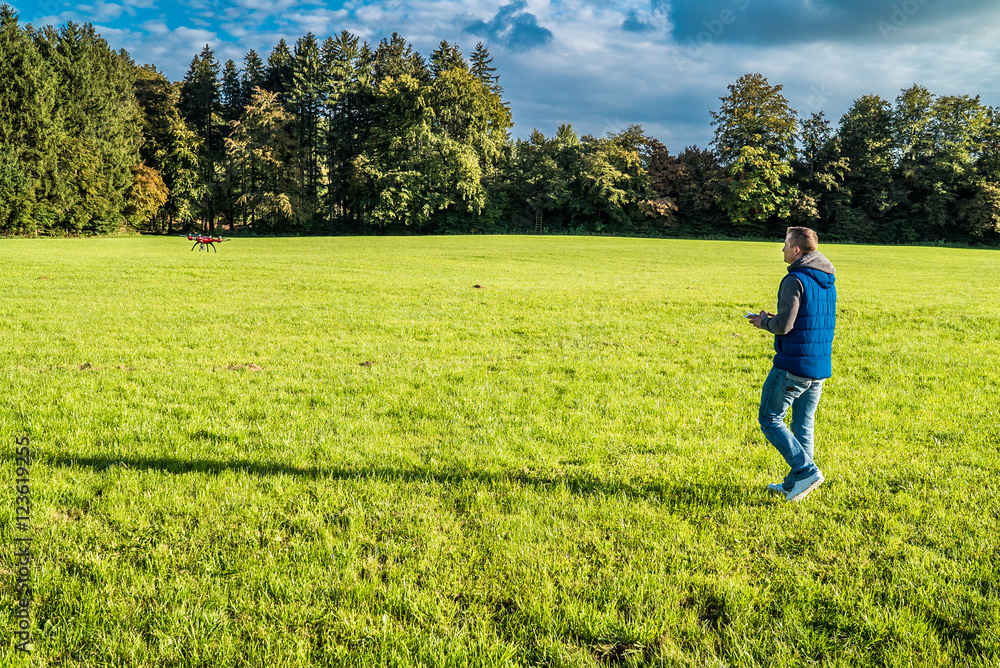 Mann auf Wiese nahe Waldstück lenkt seine Drohne