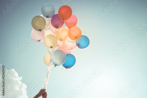 Hands of girl holding multicolored balloons done with a retro vintage filter effect, concept of happy birthday in summer and wedding honeymoon party (Vintage color tone) photo