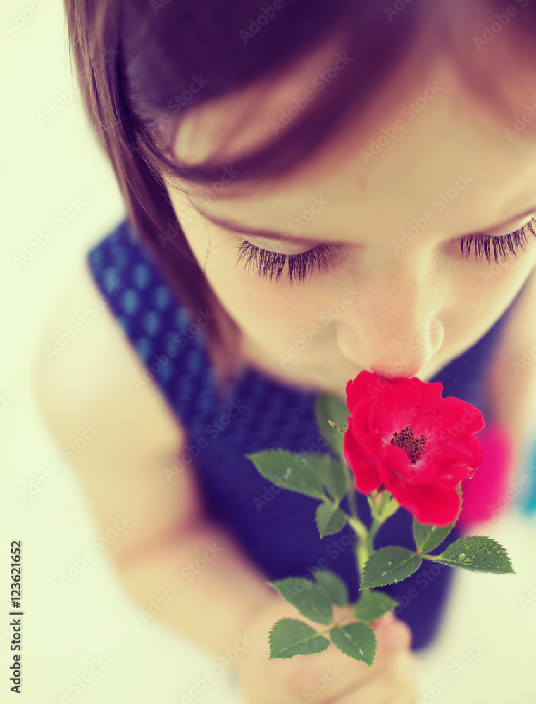 Fototapeta premium Portrait of little beautiful girl is smelling flowers