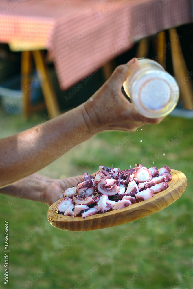 Human hands preparing plate of galician style cooked octopus. Pu