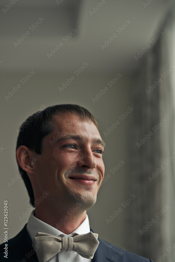 Brunette man smiles standing in the hotel room Brunette man smiles standing in the hotel room