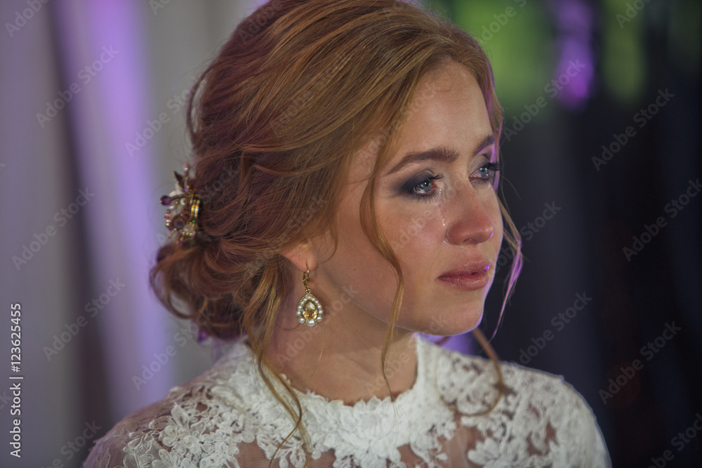 Tears pour down bride's cheek while she looks far away