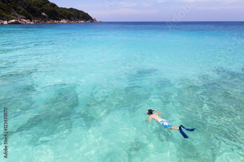 Snorkeller swimming in pristine clear turquoise tropical sea water