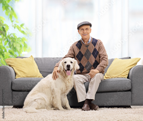 Mature man sitting on sofa and posing with his dog