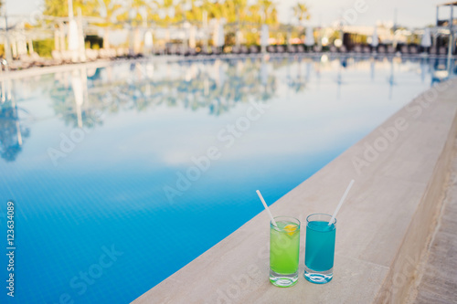 Fresh alcoholic cocktails near the swimming pool at resort. Blue and green longdrinks with ice. © anna_gorbenko