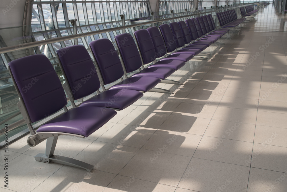 Fototapeta premium Airport terminal interior with rows of empty seats, city view an