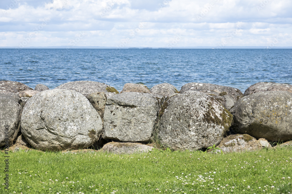 Wall of big stone blocks and water. Nature background of beautiful scenic summer landscape.