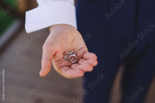 closeup of caucasian man holding the cufflinks in his hand