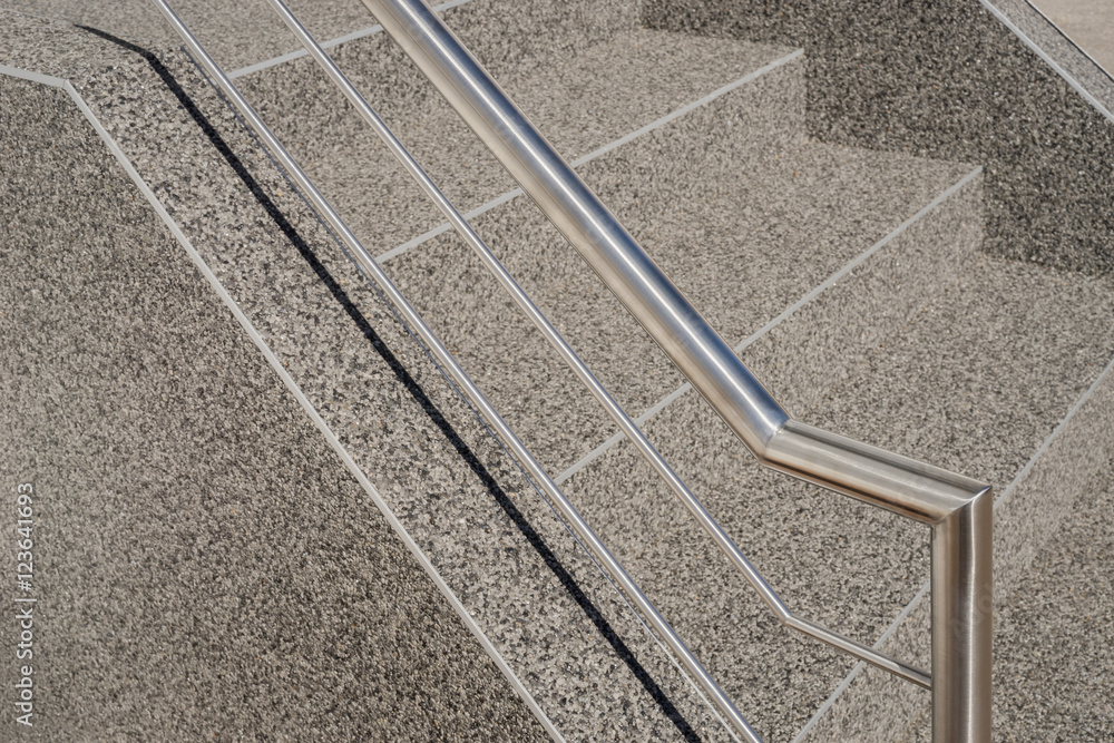 Fototapeta premium Moderner Handlauf und Edelstahlgeländer an einer Betontreppe mit Kieselbeschichtung - Contemporary handrail and stainless steel railing on a concrete staircase with gravel coating