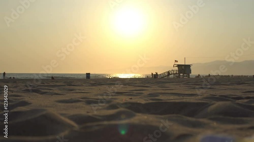 Perfect California Beach sunset, beautiful sandy beach and very few people in far distance close to the lifeguard tower. Shot in Santa Monica - Venice Beach area.