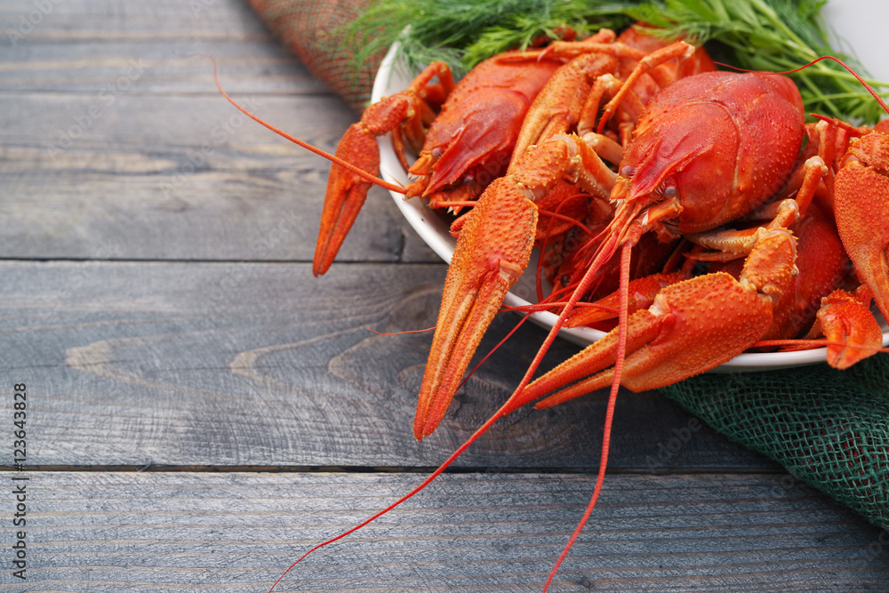 Boiled crayfish in a plate with parsley greens on a wooden background Boiled crayfish in a plate with parsley greens on a wooden background